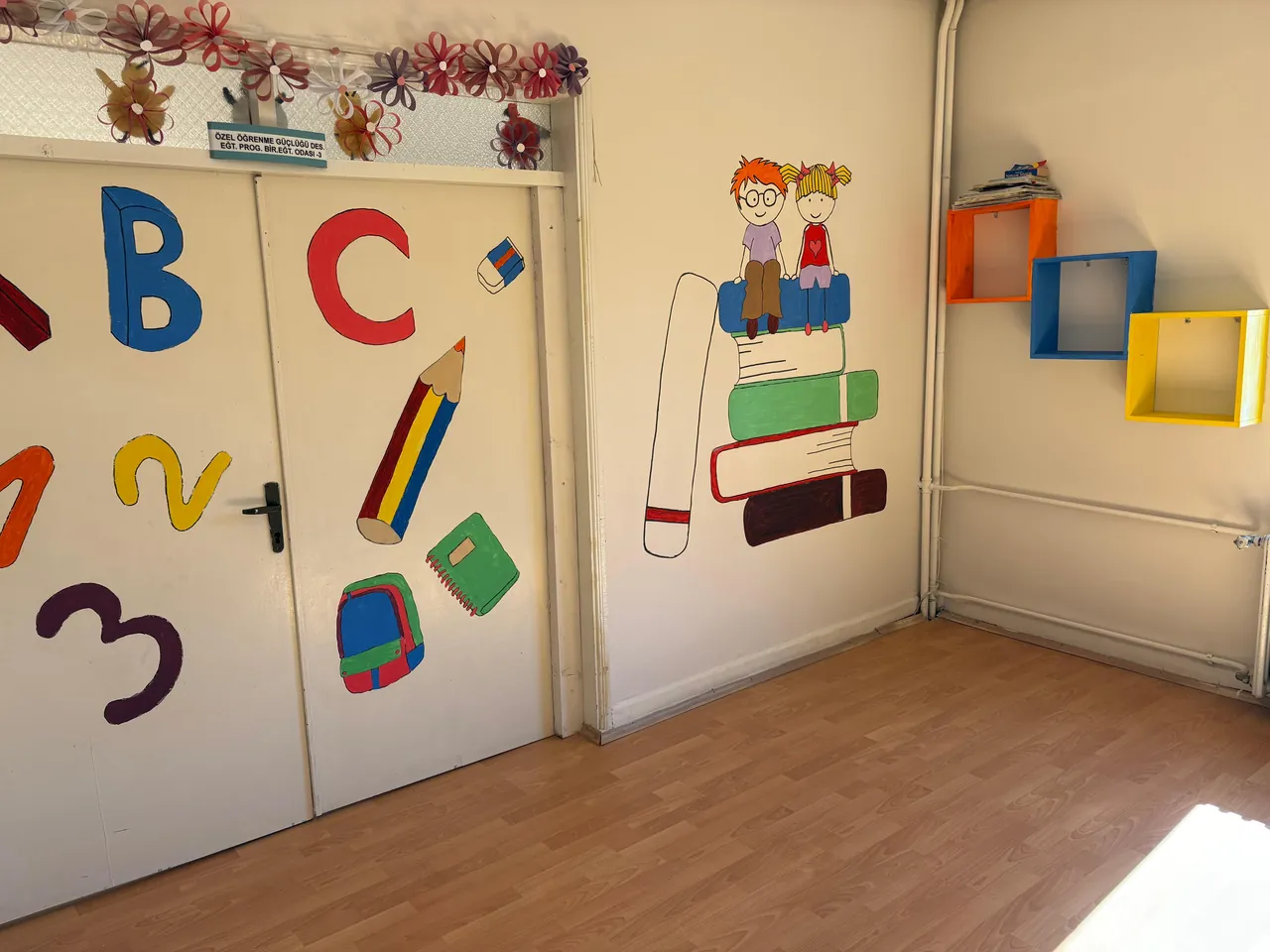 Harfler, rakamlar ve kalem resimleriyle boyanmış öğrenme güçlüğü eğitim odası kapısı